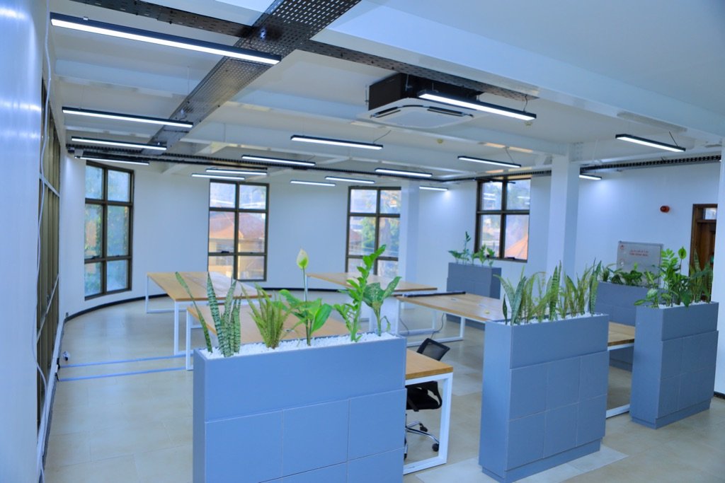 Open workspace zone with planter dividers, wooden workbenches, and natural light